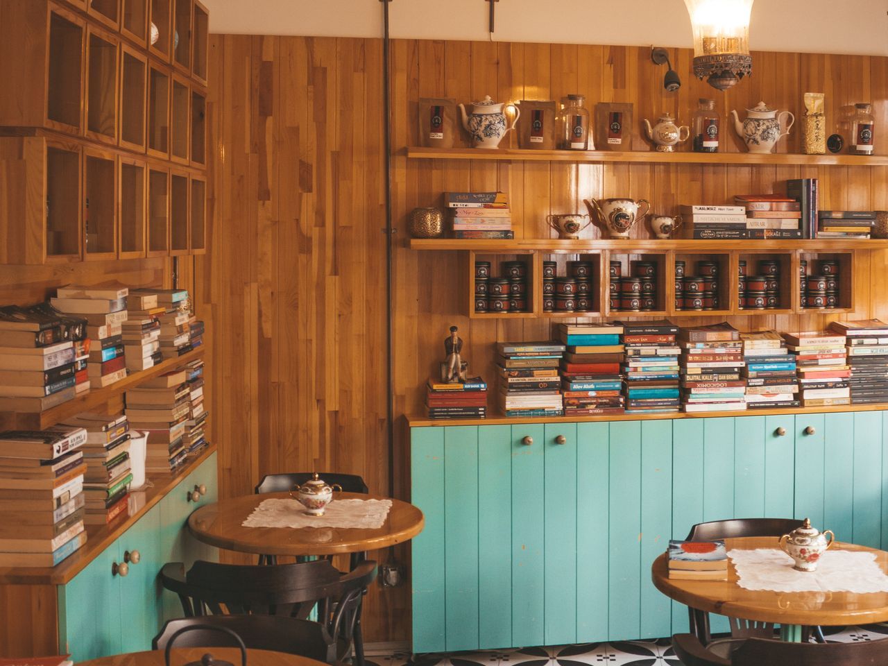 Warm wood-panelled café interior with a mint-green cabinet bar and hanging plants